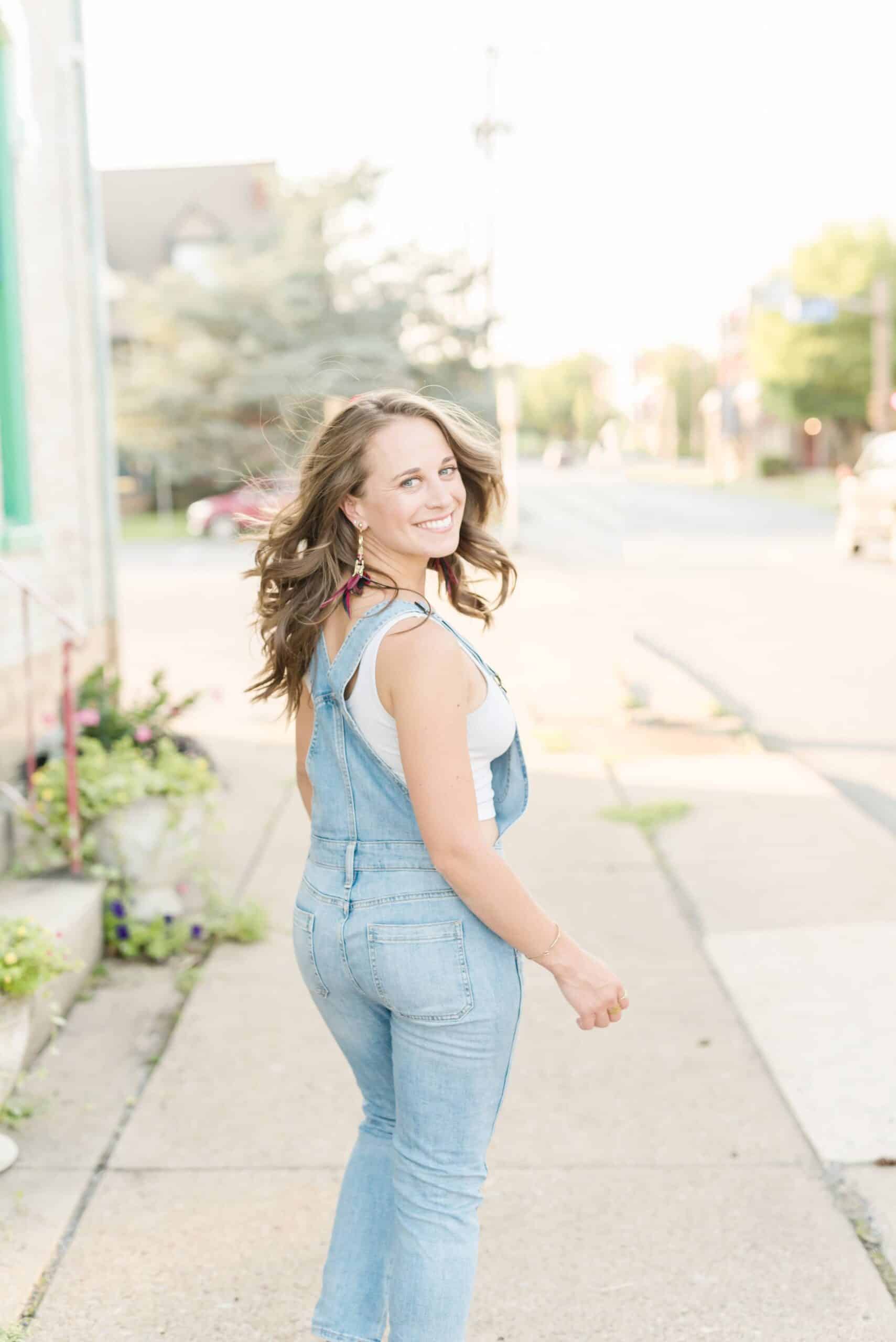 Kylie walks down a city sidewalk and looks back at the camera smiling
