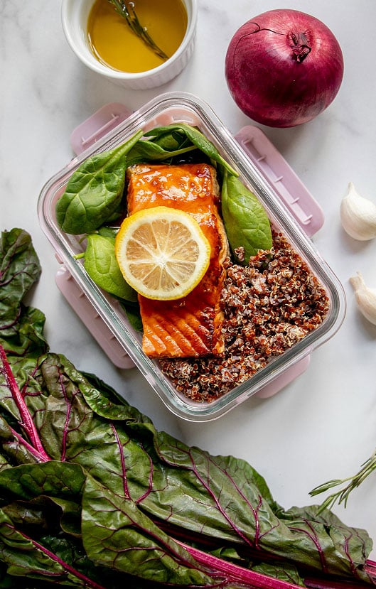 A glass container with quinoa, spinach and salmon, healthy food that might be suggested by a dietitian nutritionist in Washington DC