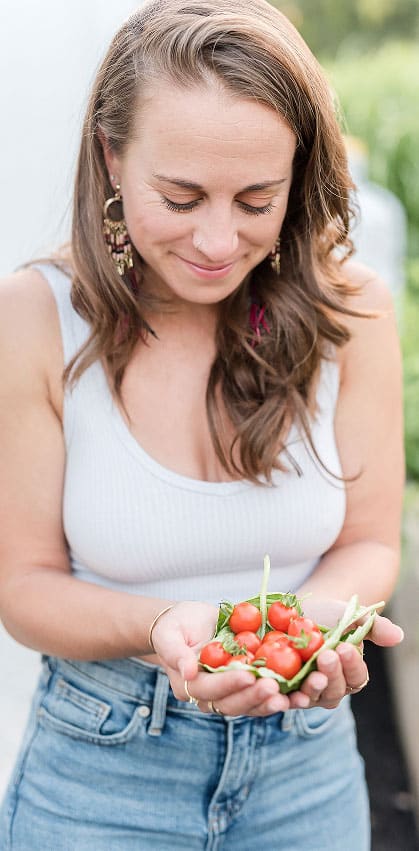 Kylie Fagnano, dietitian nutritionist in Washington DC, picks fresh basil from a gardenbed