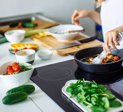 Woman sautes vegetables in her kitchen, dietitian nutritionist in Washington DC